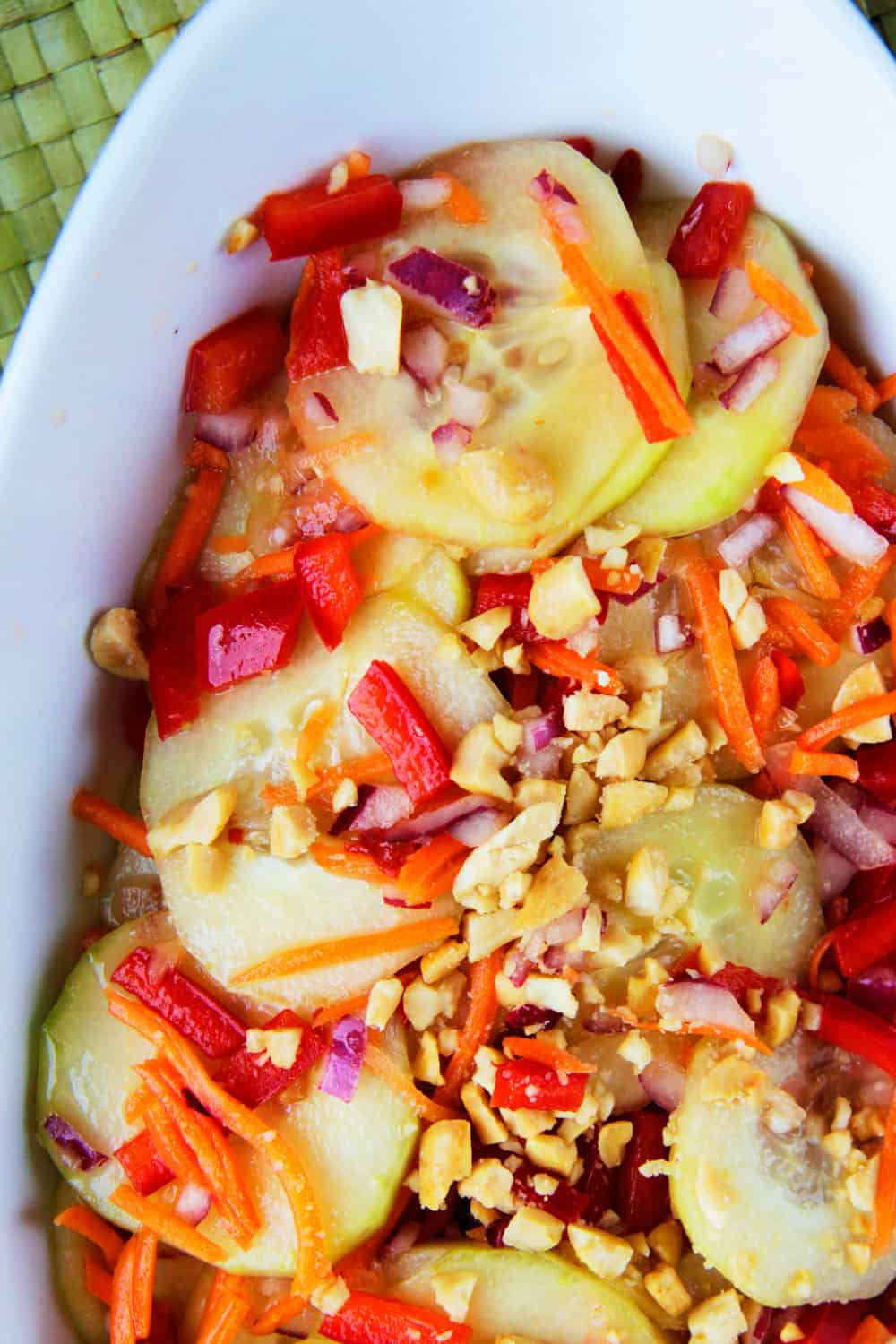Showing how to serve a Thai Cucumber Salad top shot on a white plate and bamboo place-mat.