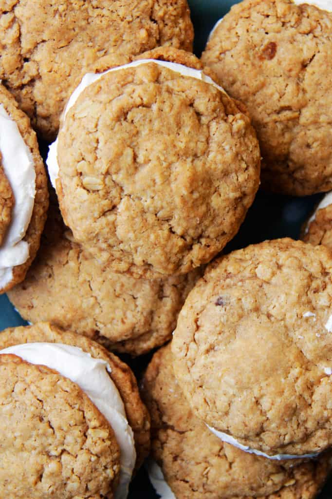 These Little Debbie's Oatmeal Cream Pies copycat are melt-in-your-mouth addicting.ย The cookies are bursting with buttery, chewy, brown sugar, molasses oatmeal which sand whichย a luscious creamy vanilla center.ย After one bite, you will never want to buy Little Debbies' Oatmeal Cream Pies ever again! top view of homemade oatmeal cream pies with cream filling