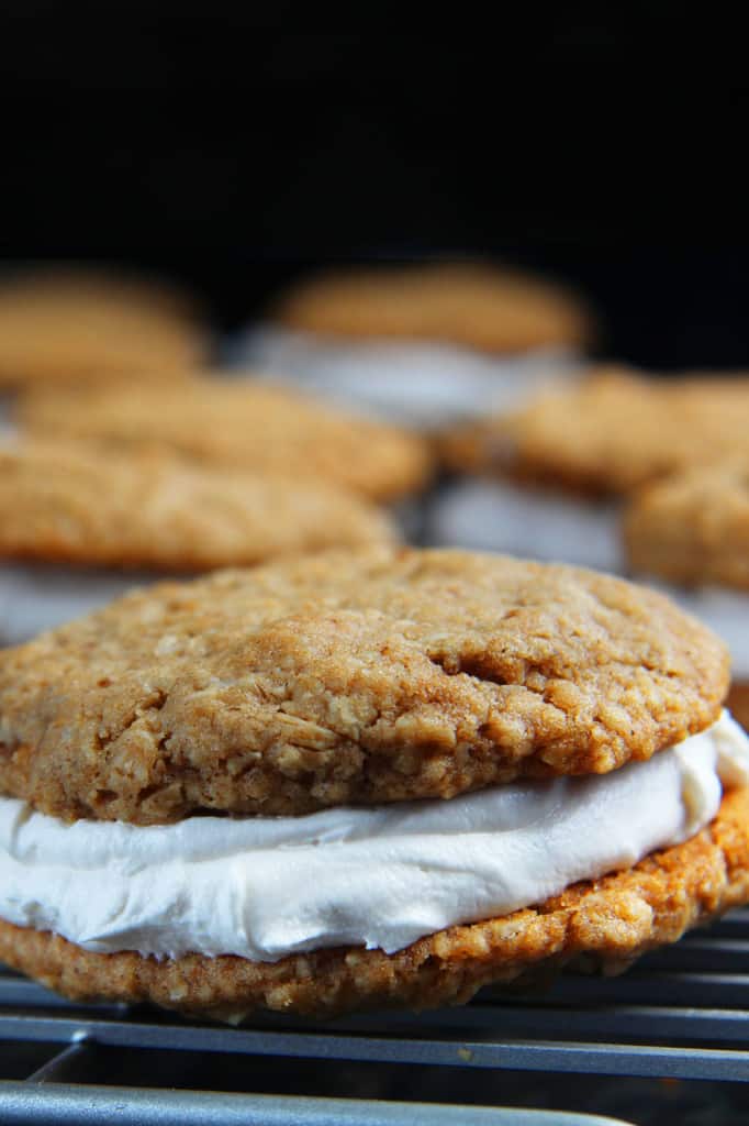 These Little Debbie's Oatmeal Cream Pies copycat are melt-in-your-mouth addicting.ย The cookies are bursting with buttery, chewy, brown sugar, molasses oatmeal which sand whichย a luscious creamy vanilla center.ย After one bite, you will never want to buy Little Debbies' Oatmeal Cream Pies ever again! up close of chewy oatmeal cream pies with cream filling