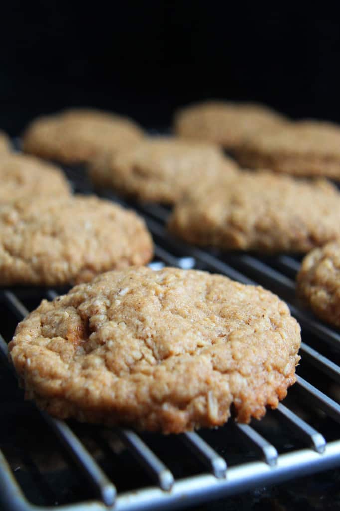 These Little Debbie's Oatmeal Cream Pies copycat are melt-in-your-mouth addicting.ย The cookies are bursting with buttery, chewy, brown sugar, molasses oatmeal which sand whichย a luscious creamy vanilla center.ย After one bite, you will never want to buy Little Debbies' Oatmeal Cream Pies ever again! side view of homemade oatmeal cream pies cooling on a cooling rack