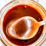 top view of a spoon dipping into easy caramel sauce in a jar