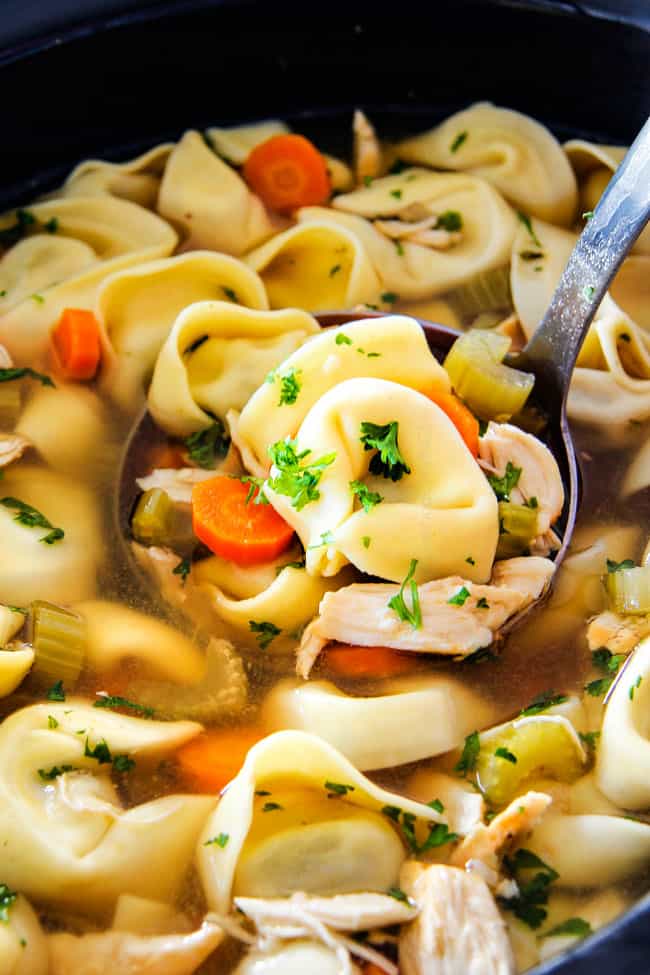 This is the BEST Slow Cooker Chicken Tortellini Soup you will ever try!ย It's super easy, seasoned to perfection and a comforting, satisfying dinner any night of the week!ย ย showing how to make Chicken tortellini soup by placing chicken in crockpot