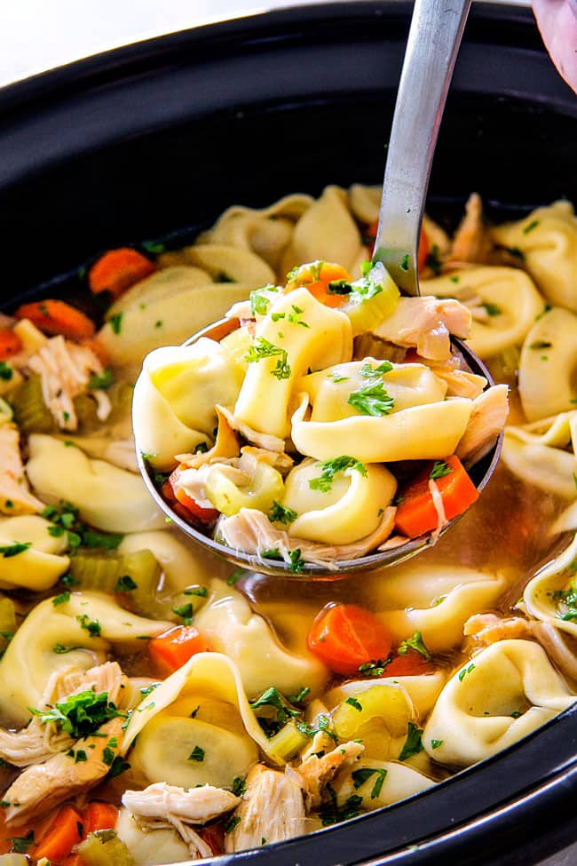 This is the BEST Slow Cooker Chicken Tortellini Soup you will ever try!ย It's super easy, seasoned to perfection and a comforting, satisfying dinner any night of the week!ย ย side view of Chicken Tortellini Soup with cheese tortellini, carrots, celery, onions, garlic and spicess