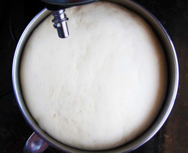 Showing how to make Homemade Pizza Dough by mixing dough in a mixing bowl allowing the dough to rise.