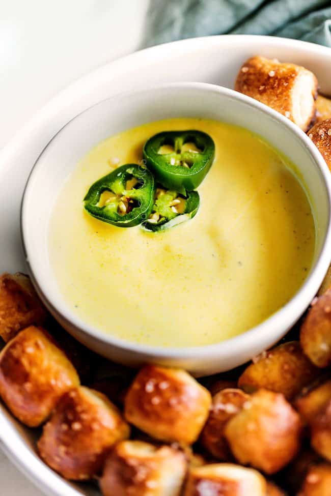 a bowl of cheese dip surrounded by homemade pretzel bites
