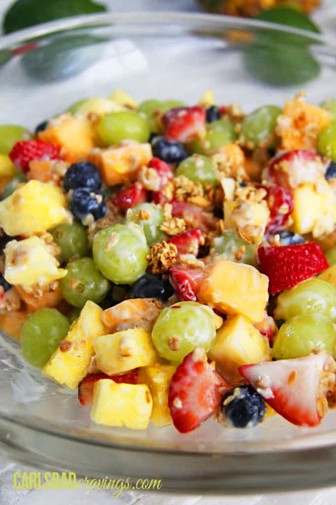 showing how to make fruit salad with yogurt by adding granola