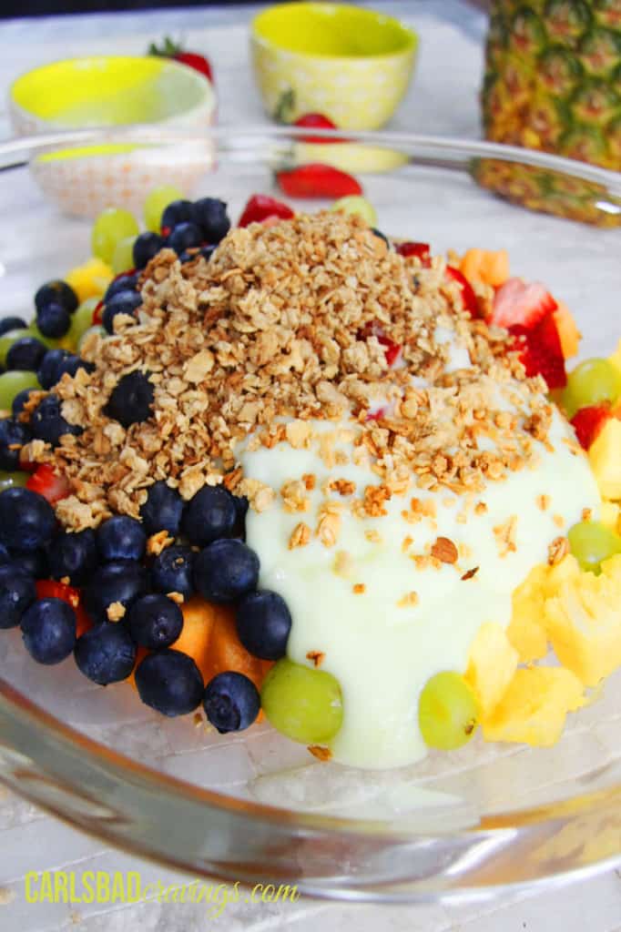 showing how to make fruit salad with yogurt by tossing fruit with yogurt