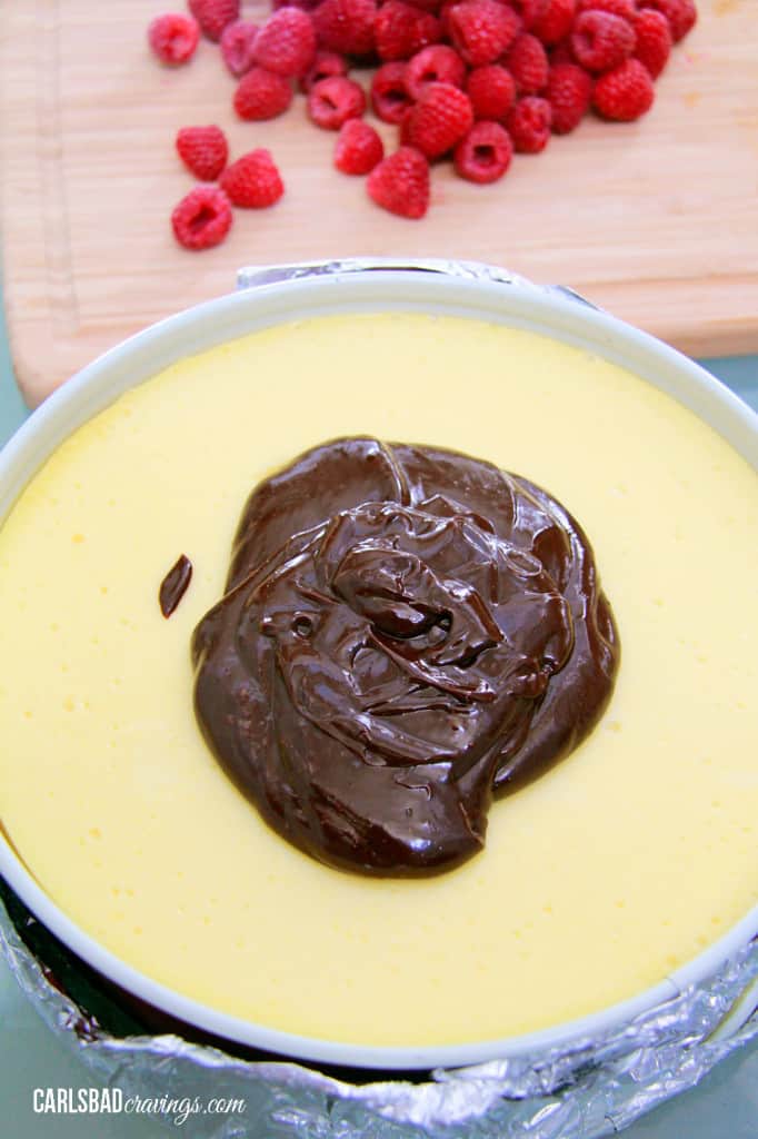 pile of chocolate ganache on a baked cheesecake, about to be swirled on top 