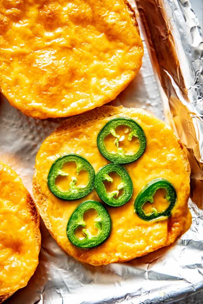 showing how to make burgers by melting cheese on the buns