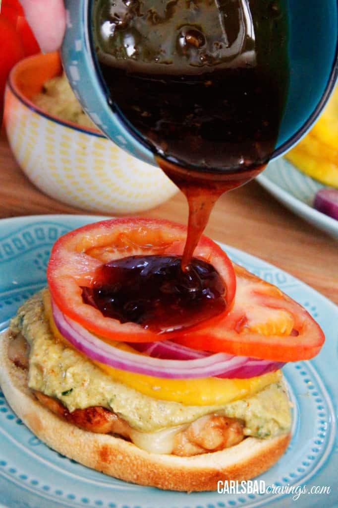 showing how to make Teriyaki Chicken Sandwiches by pouring teriyaki sauce on top of sandwich