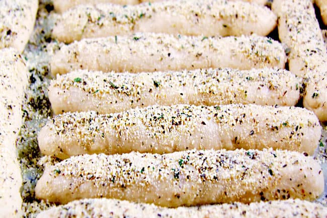 showing how to make breadsticks by adding garlic herb seasoning