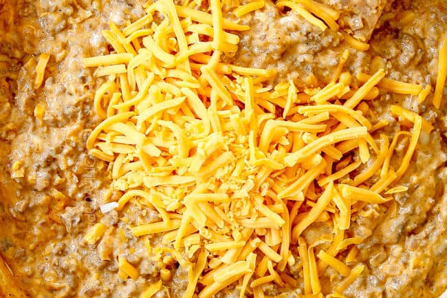 showing how to make buffalo mac and cheese by stirring mozzarella cheese and cheddar cheese into sauce