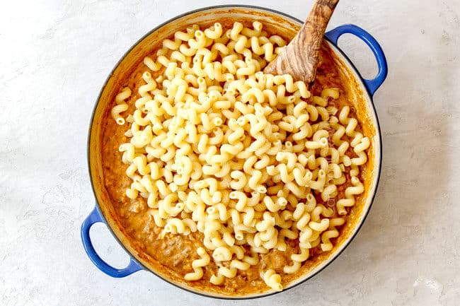 showing how to make buffalo mac and cheese by stirring in pasta