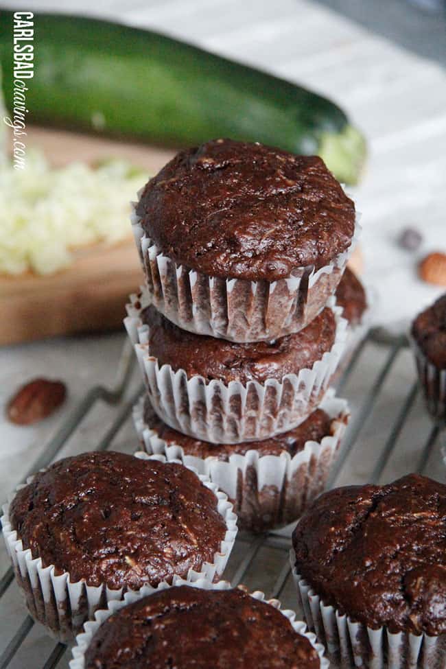 Chocolate Zucchini Muffins with DOUBLE the CHOCOLATE, ZERO added fat and a whole lot of yum!! This Chocolate Zucchini Muffins Recipe is baked with applesauce and vanilla yogurt that are crazy moist and chocolaty!ย You will devour these by the handfuls - becauseย you can! a stack of chocolate zucchini muffins