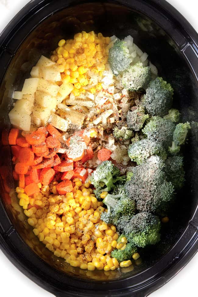 showing how to make crockpot corn chowder in the slow cooker by adding chicken, corn, carrots, potatoes, onions, broccoli to crockpot