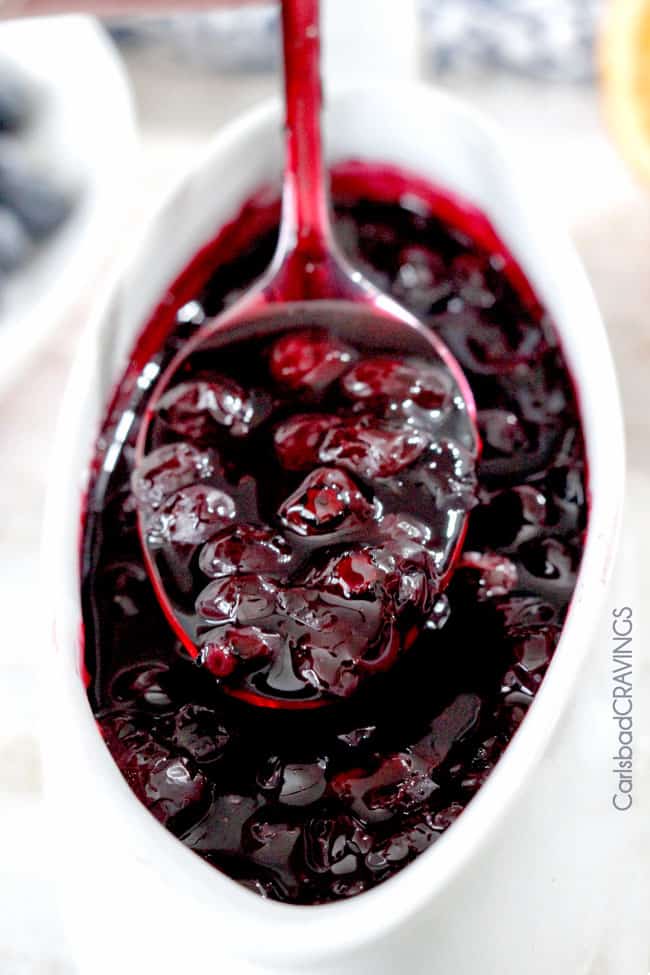 Blueberry Cheesecake Topping in a white serving container with a spoon