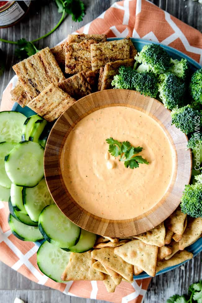 Top view of Broccoli and vegetables around a bowl of Roasted Red Pepper Feta Dip.