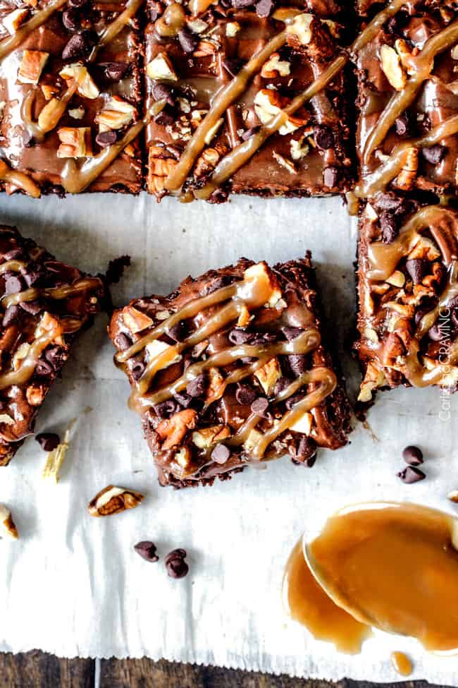 Crazy moist Poke Turtle Brownies seeping with pockets of caramel, infused with pecans and chocolate chips, smothered in the BEST chocolate frosting and topped with more caramel. the best brownies EVER! top view of salted caramel turtle brownies sliced into squares with salted caramel drizzled on top