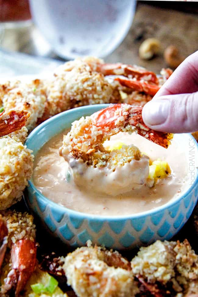 Coconut Shrimp being dipped in sauce on a platter.