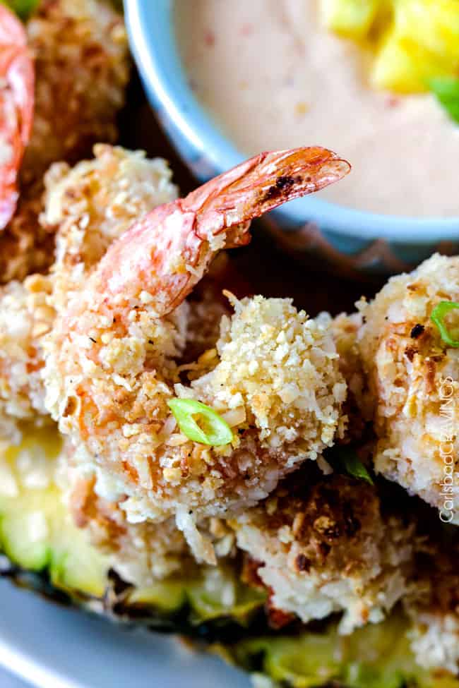 Baked crunchy, juicy Coconut Cashew Shrimp with Pineapple Sweet Chili Dip way better than takeout without the extra fat or cost!Baked crunchy, juicy Cashew Coconut Shrimp with Pineapple Sweet Chili Dip way better than takeout without the extra fat or cost! Close up of Coconut Shrimp on a platter next to dipping sauce.