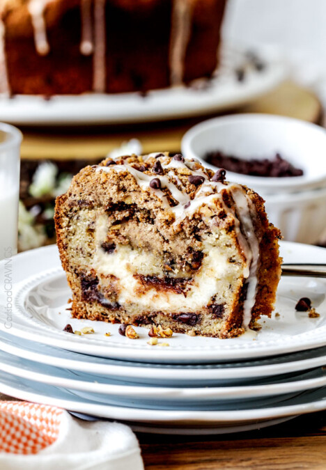 The best Banana ANYTHING ever! Moist Banana Coffee Cake riddled with chocolate chips and walnuts (optional) with an INCREDIBLY creamy cheesecake-like cream cheese filling all topped with brown sugar walnut streusel and vanilla drizzle.