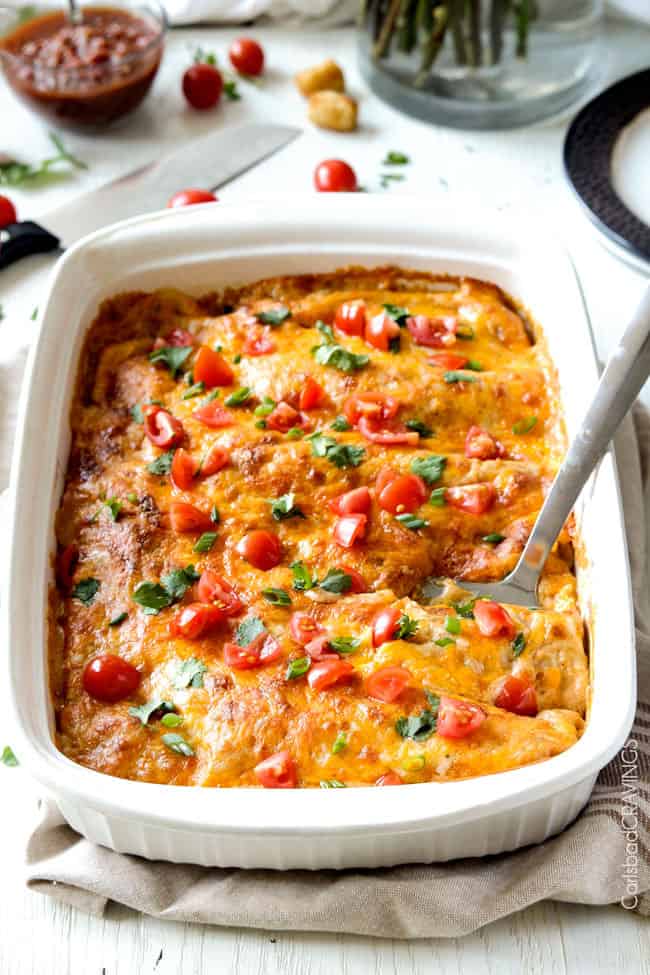 Easy, hearty Breakfast Enchiladas stuffed with your favorite breakfast ingredients then smothered with intoxicatingly delicious Creamy Salsa Sauce! These enchiladas are totally customizable, perfect for your leftover holiday ham AND you can assemble the night before and bake the next day! front view of a white pan of Breakfast Enchiladas with eggs, ham bacon, cheese