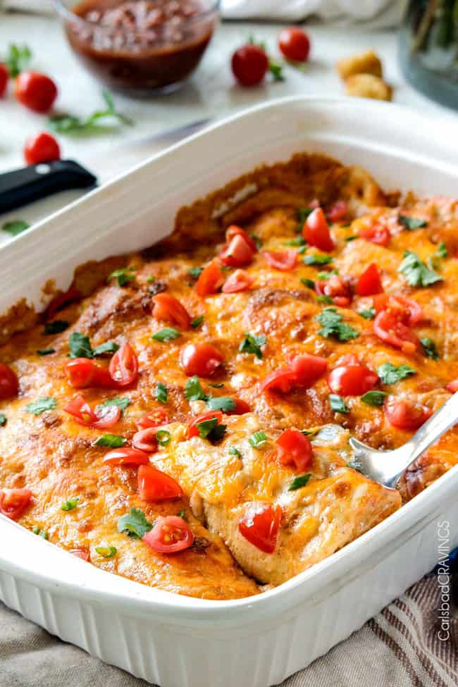 Easy, hearty Breakfast Enchiladas stuffed with your favorite breakfast ingredients then smothered with intoxicatingly delicious Creamy Salsa Sauce! These enchiladas are totally customizable, perfect for your leftover holiday ham AND you can assemble the night before and bake the next day! side view of breakfast enchiladas garnished with tomatoes