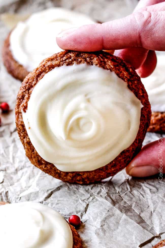 Holding a single Gingersnap Cookie with Eggnog Frosting.