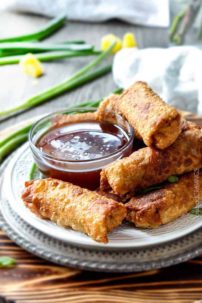 Sweet and Sour Chicken Egg are the best egg rolls Iโve ever had with the best sweet and sour sauce! And made extra fast with the food processor. I am bringing these to all my holiday parties! #appetizer #NewYears #Christmas a stack of chicken egg rolls on a plate