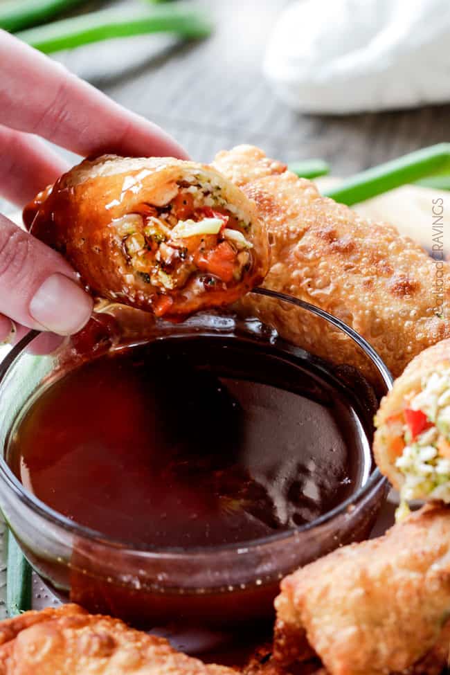 Sweet and Sour Chicken Egg are the best egg rolls Iโve ever had with the best sweet and sour sauce! And made extra fast with the food processor. I am bringing these to all my holiday parties! #appetizer #NewYears #Christmas dipping a chicken egg roll in sweet and sour sauce