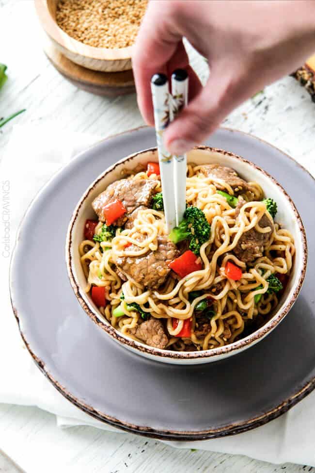 Beef and Broccoli Noodle Bowls being scooped with chopsticks.