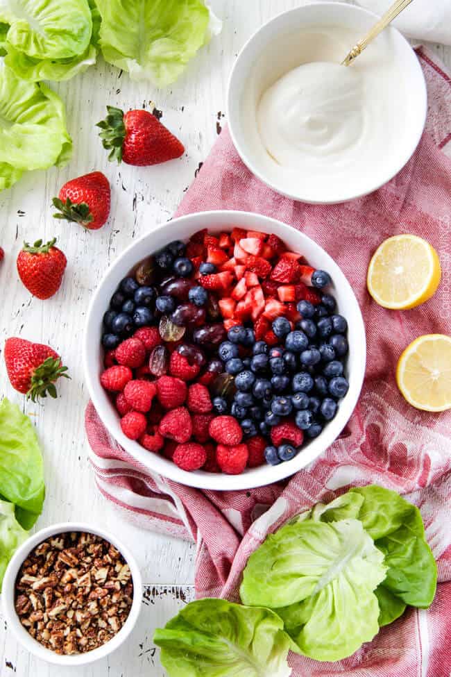 Showing how to make Berry Salad by mixing berries in a white bowl.