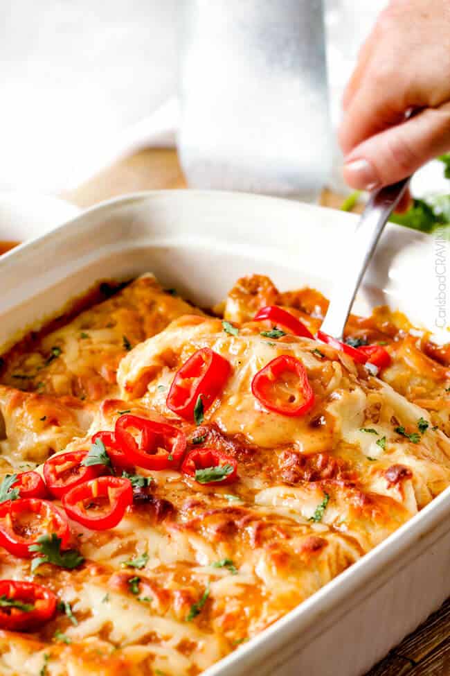 These Sweet chili Chicken Enchiladas are AMAZING! My whole family loves them and I always make them for company. The sauce is out of this world! a spatula digging into chili enchiladas with sweet chili enchiladas