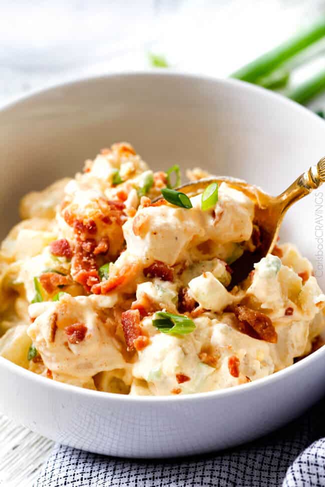 Everyone needs the best potato salad recipe and this is it! so creamy and flavorful and disappears in minutes whenever I take it any where - everyone always asks for the recipe!! a gold spoon taking a bite of the best homemade potato salad recipe