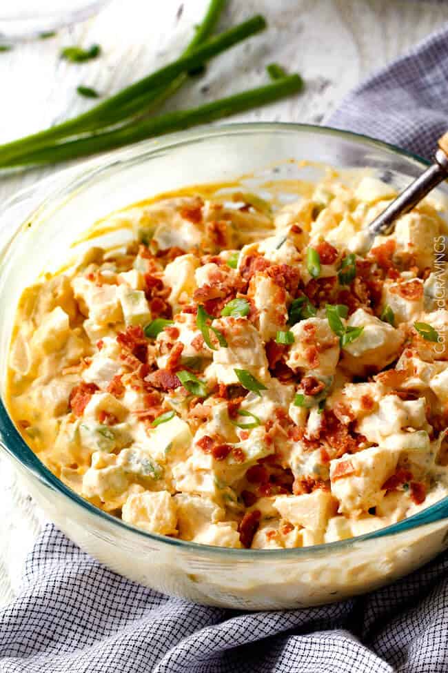 Everyone needs the best potato salad recipe and this is it! so creamy and flavorful and disappears in minutes whenever I take it any where - everyone always asks for the recipe!! side view of a glass bowl of easy potato salad garnished with bacon and green onions