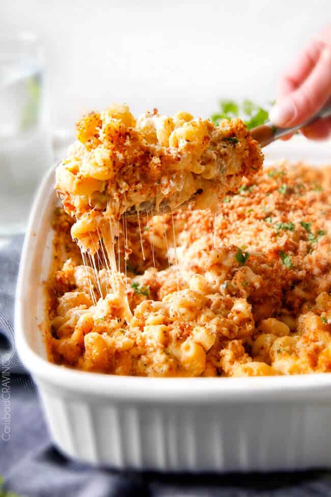 A cheesy scoop of Million Dollar Macaroni and Cheese coming out of a pan.