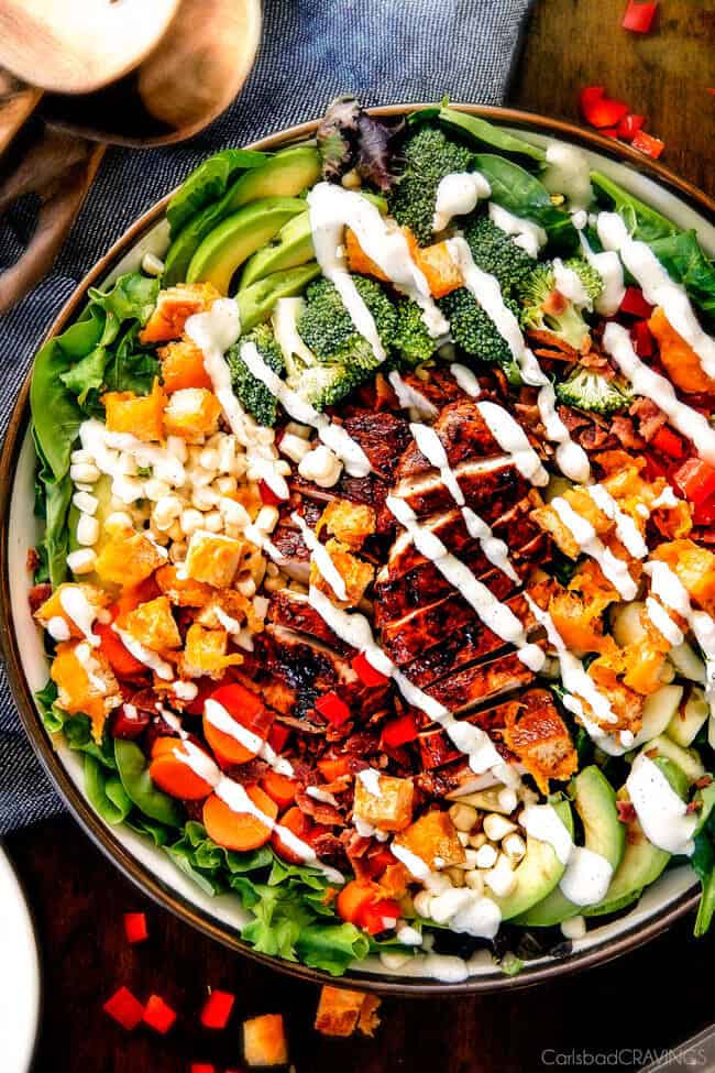Bacon Ranch Chicken Salad in a bowl with dressing poured on top.