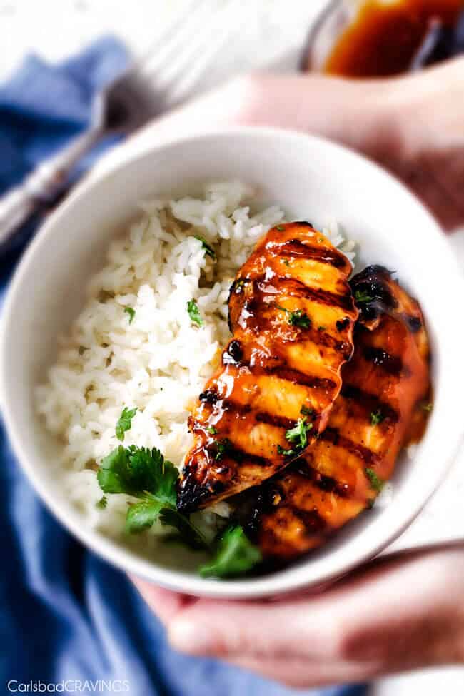 two pieces of grilled pineapple chicken on bed of rice in white bowl