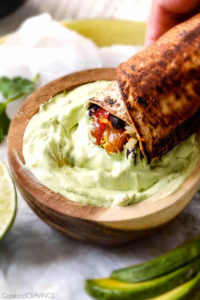 Chicken Fajita Wrap being dipped in an avocado cream sauce.