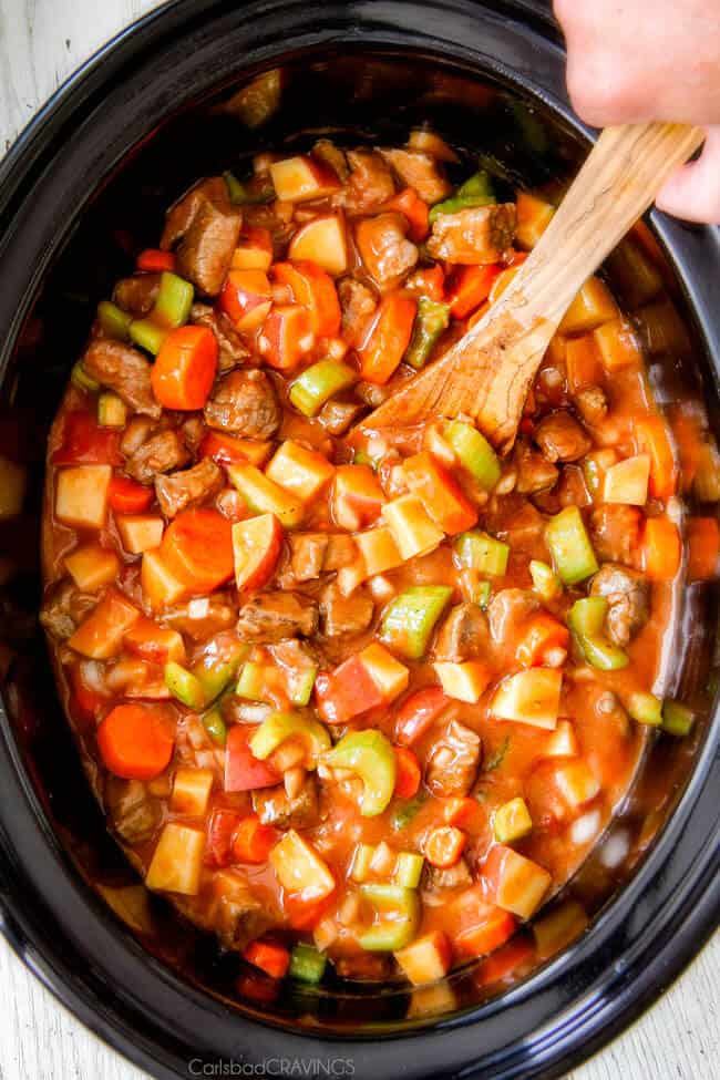 showing how to make crockpot beef stew by adding gravy to the slow cooker