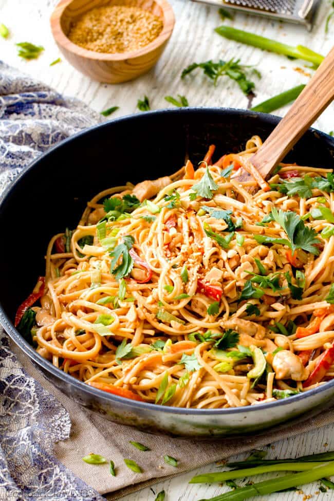 30 Minute Peanut Sesame Noodles (with Chicken and Veggies) - super quick and easy meal all in one with the most amazing creamy peanut sesame sauce you will crave for days! Stirring sesame sauce into sesame noodles in a black skillet