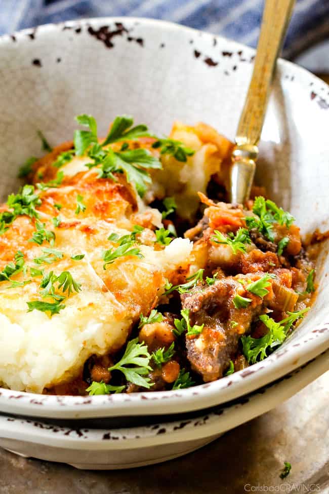Savory, comforting Boneless Short Rib Shepherd's Pie elevates shepherd's (or cottage pie) to a whole new level with melt in your mouth meat and Swiss Gruyere Mashed Potatoes! This is guaranteed to be a new family favorite!!! up close of serving of the best Shepherd's Pie recipe in a bowl