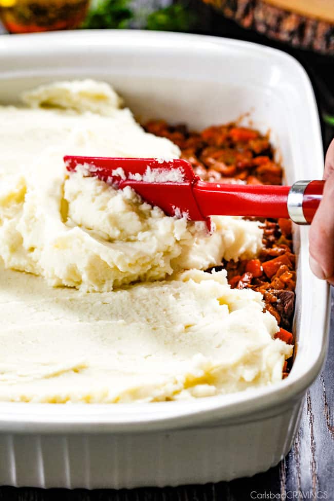 showing how to make shepherds pie by spreading potatoes over the top