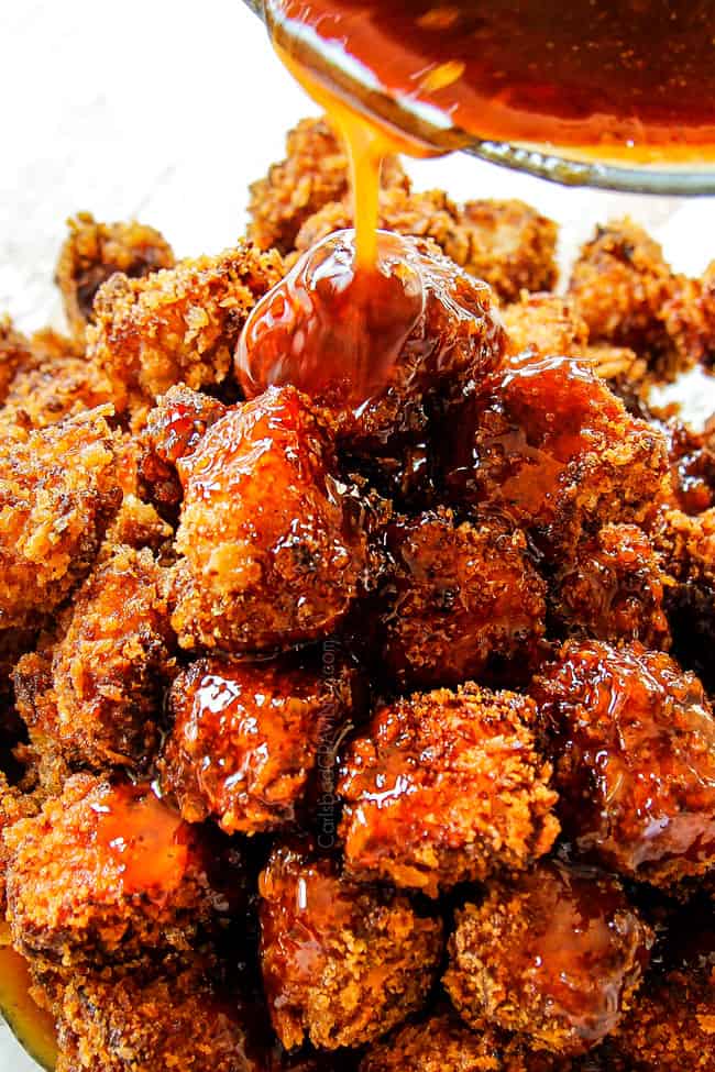 showing how to make Chinese Lemon Chicken by drizzling fried chicken pieces with lemon sauce