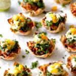 Salsa Verde Honey Lime Chicken Taco Cups - the cheesy sweet heat packed into these crispy, taco cups is so addicting and the mango guacamole is the perfect finishing touch! Whenever I serve these for an appetizer they get gobbled right up!
