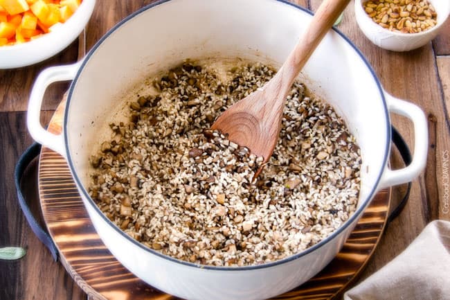 No Babysitting, easy, creamy BAKED Butternut Squash Risotto with Pine Nuts and Pepper Jack! This simple to prepare risotto is wonderfully smooth and creamy, seasoned to perfection and is absolutely fool proof! It makes the most amazing Thanksgiving or holiday side but is easy enough for every day! showing how to make Butternut Squash Risotto by sauteeing mushrooms, shallots, garlic and rice in a white stock pot