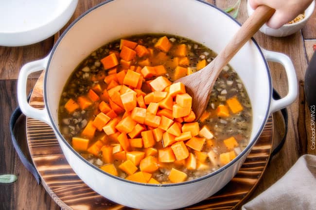 No Babysitting, easy, creamy BAKED Butternut Squash Risotto with Pine Nuts and Pepper Jack! This simple to prepare risotto is wonderfully smooth and creamy, seasoned to perfection and is absolutely fool proof! It makes the most amazing Thanksgiving or holiday side but is easy enough for every day! showing how to make Butternut Squash Risotto by stirring in uncooked squash to rice in white pot.