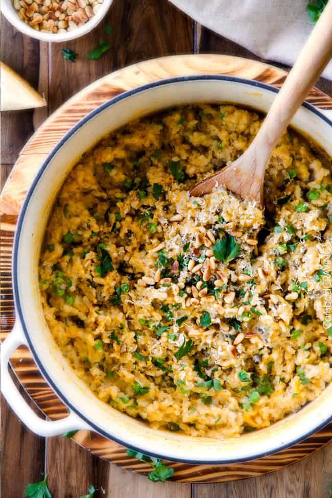 No Babysitting, easy, creamy BAKED Butternut Squash Risotto with Pine Nuts and Pepper Jack! This simple to prepare risotto is wonderfully smooth and creamy, seasoned to perfection and is absolutely fool proof! It makes the most amazing Thanksgiving or holiday side but is easy enough for every day! top view of BAKED Butternut Squash Risotto in a large white Dutch oven with peas, mushrooms and pine nuts