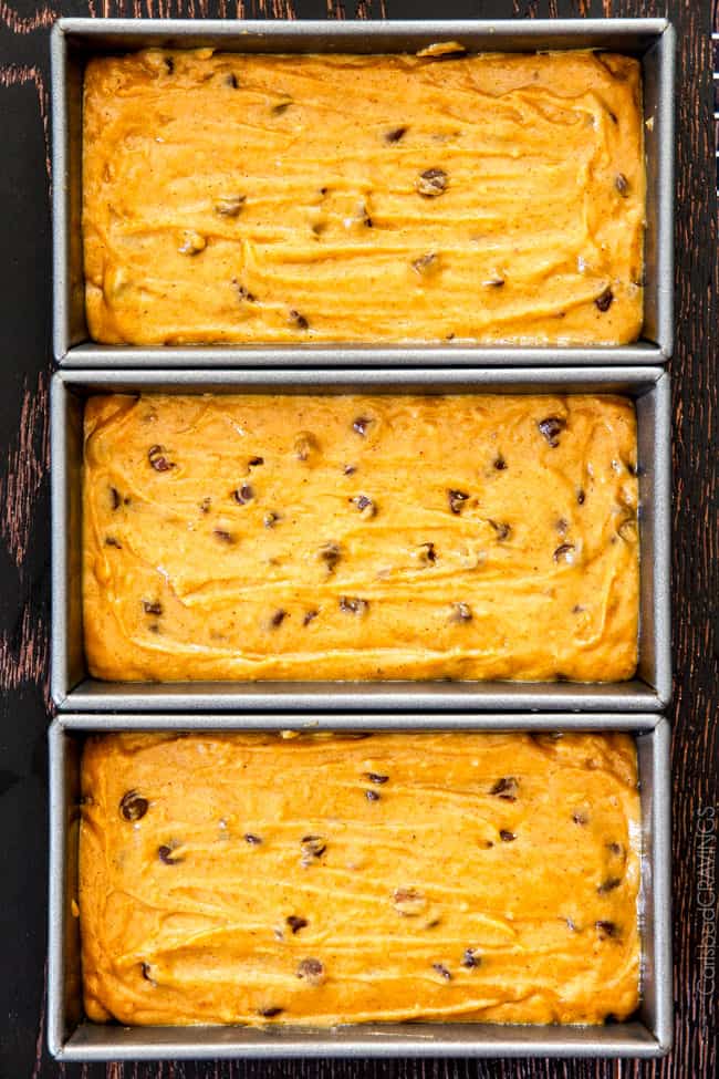 My Momโs Famous Chocolate Chip Pumpkin Bread! So incredibly moist, infused with cinnamon, cloves and nutmeg with only 2 bowls and one whisk required! Everyone will BEG you for this recipe! showing how to make Libby's pumpkin bread by pouring pumpkin batter into loaf pans