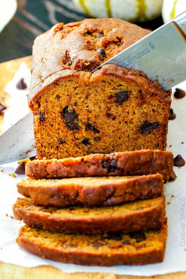My Momโs Famous Chocolate Chip Pumpkin Bread! So incredibly moist, infused with cinnamon, cloves and nutmeg with only 2 bowls and one whisk required! Everyone will BEG you for this recipe! showing how to make best pumpkin bread by slicing it on a cutting board